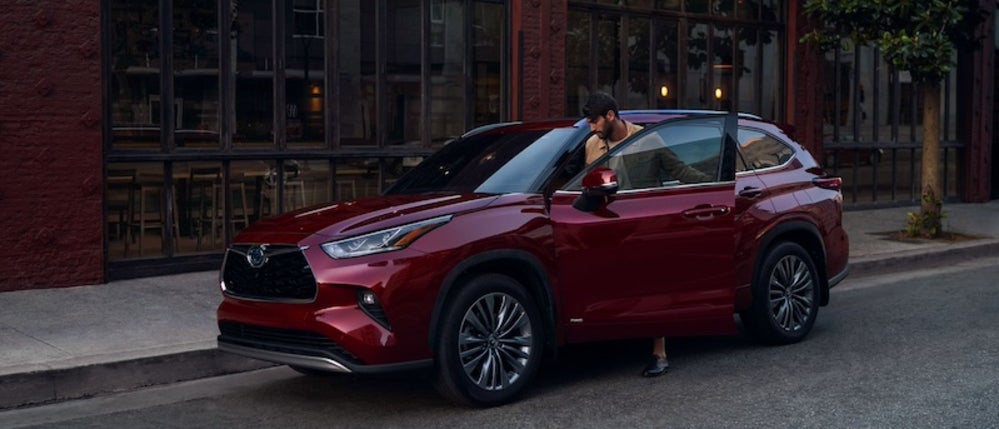 A person entering a Toyota Highlander parked on the street