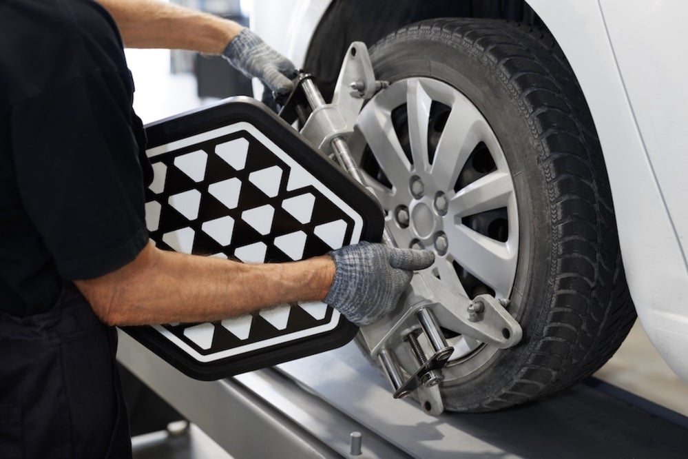 A mechanic using wheel alignment equipment on a vehicle’s wheel