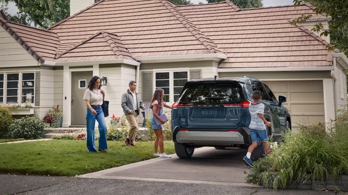 A family walking from their house to their blue 2026 Toyota RAV4 SUV