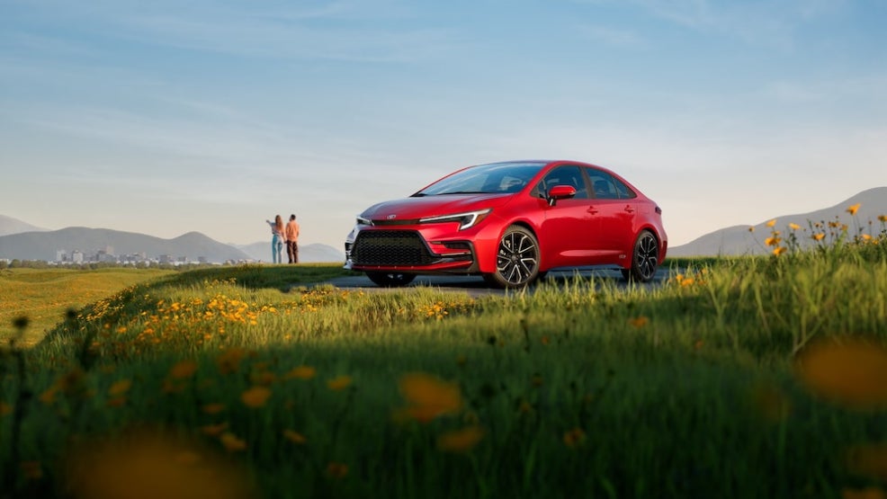 A red Toyota Corolla sedan parked in a field