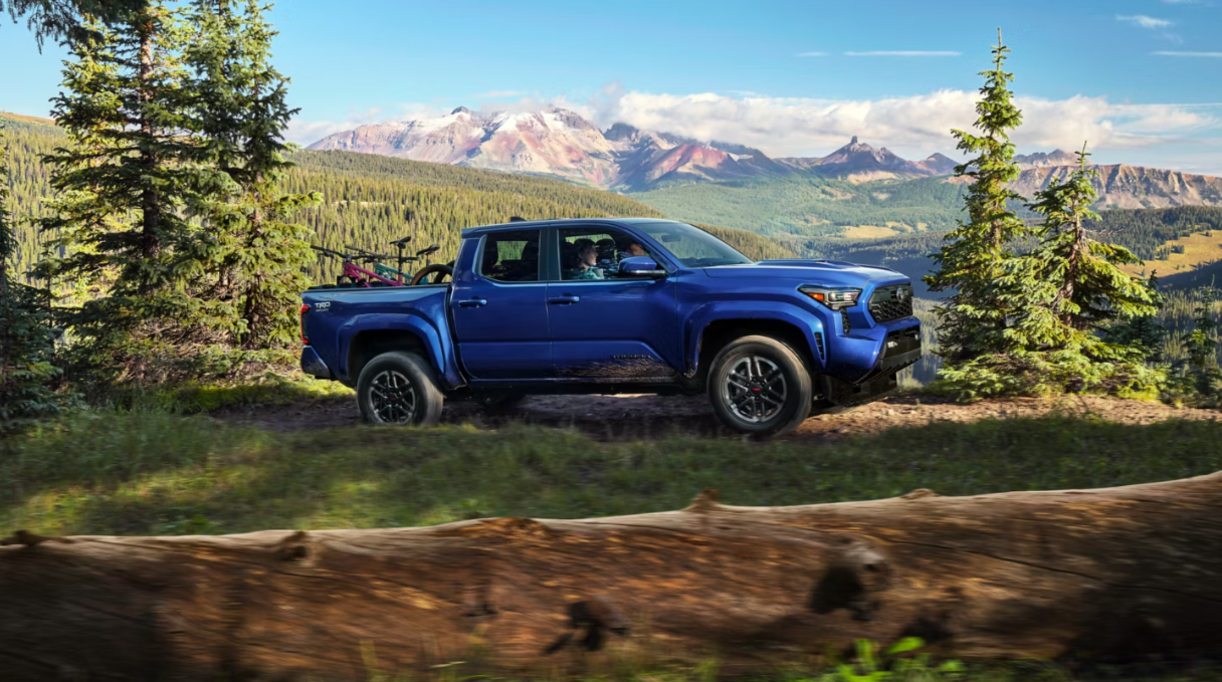 Side profile of a blue Toyota Tacoma in a mountainous setting