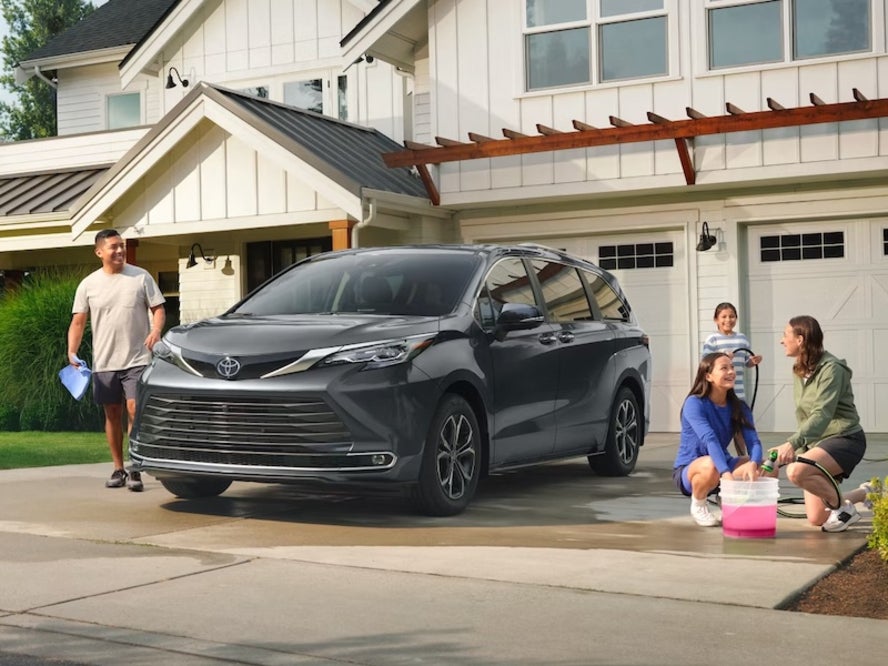 A family washing their gray 2026 Toyota Sienna minivan in their driveway