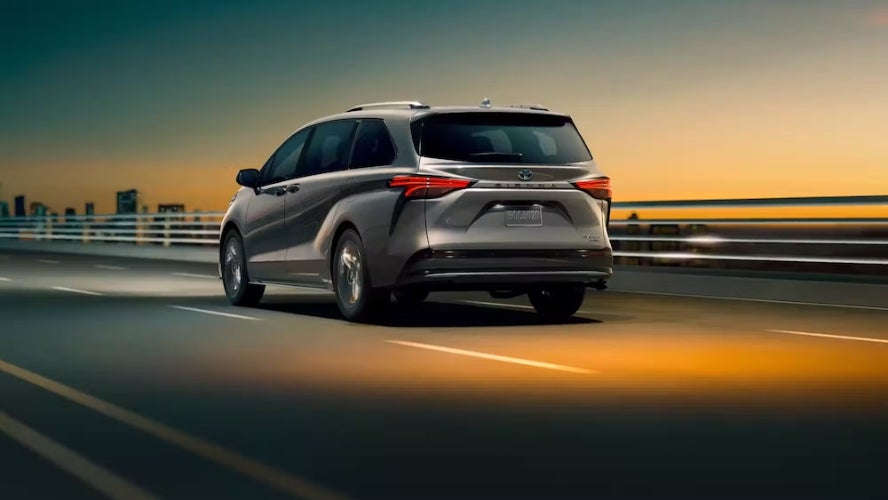 A gray 2025 Toyota Sienna SUV driving down a highway at sunset