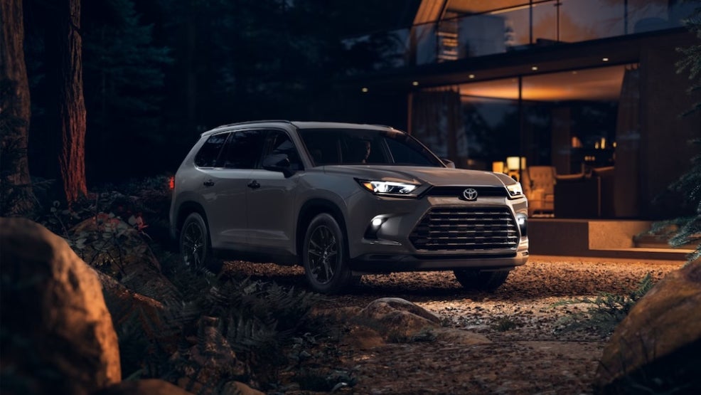 A gray 2025 Toyota Grand Highlander parked outside a cabin at night