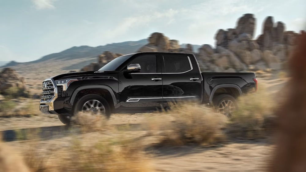 A black 2026 Toyota Tundra pickup truck driving through desert brush